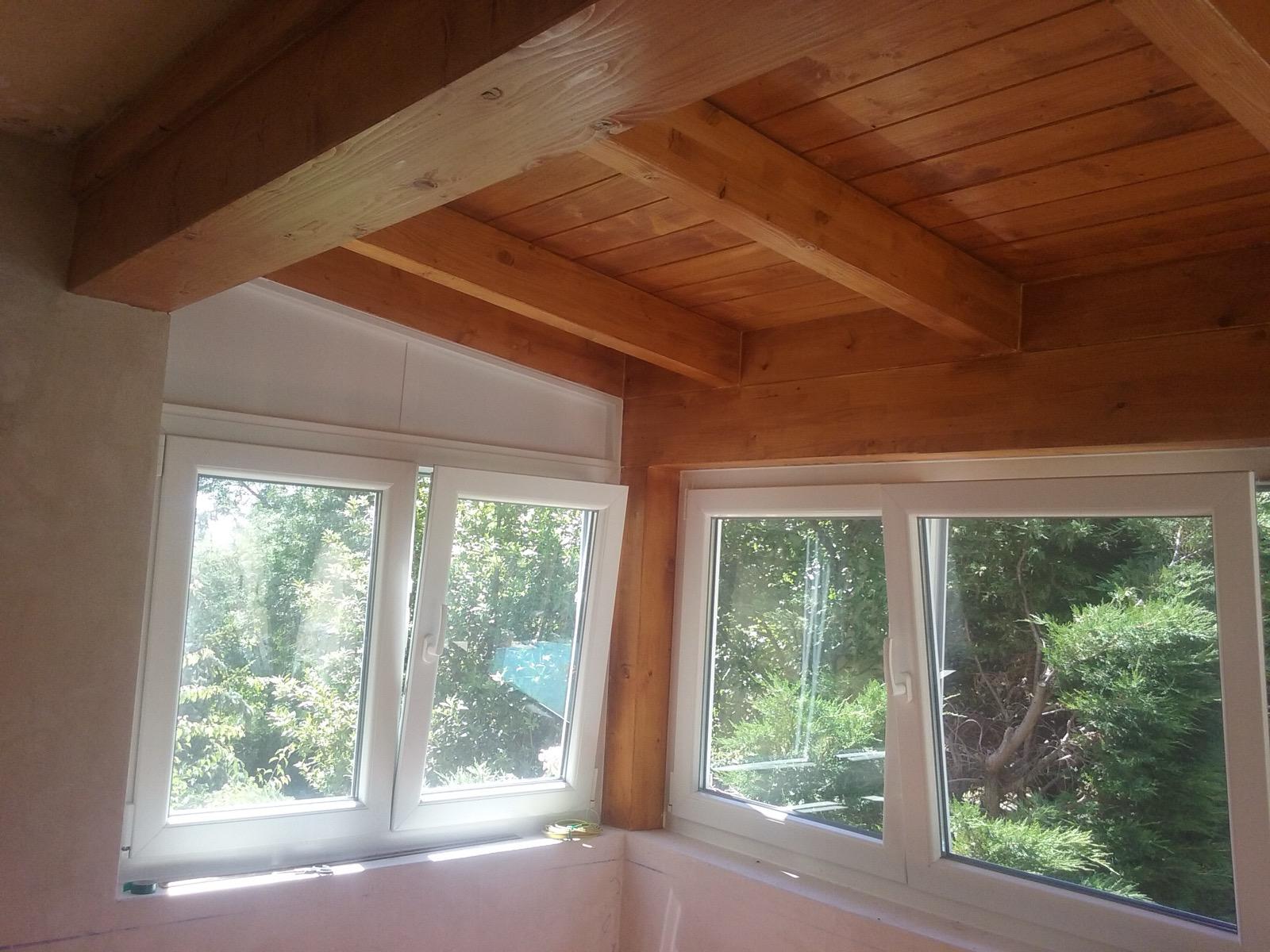 Vista interior del cerramiento de porche con vigas de madera y ventanas de PVC en Becerril