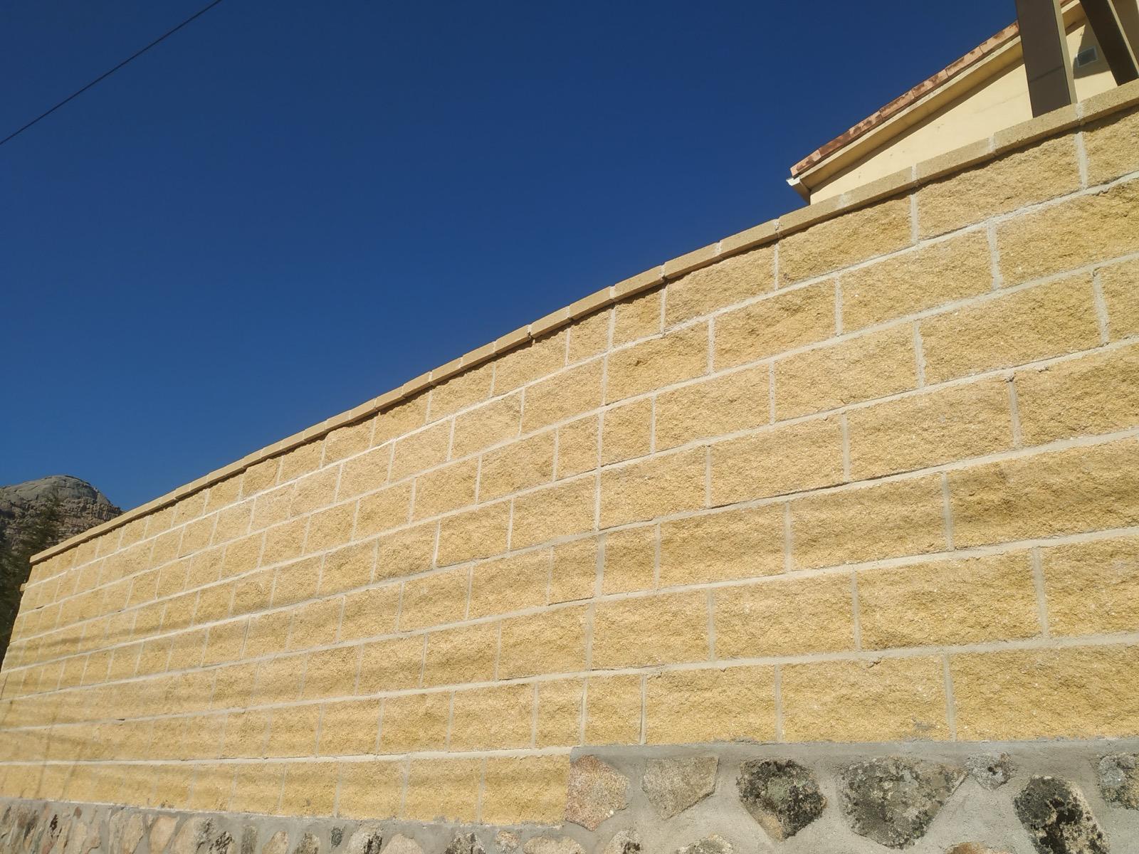 Muro exterior de bloques de hormigón split sobre zócalo de piedra natural en Moralzarzal