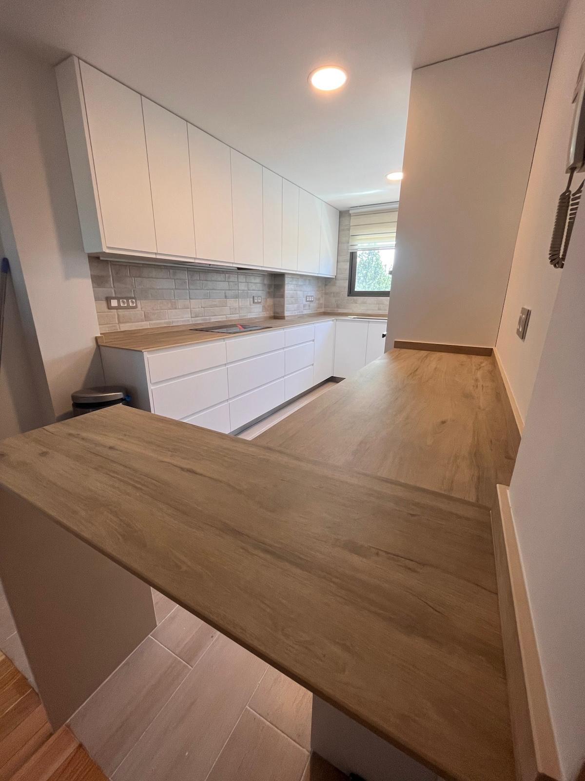 Reforma de cocina moderna con muebles blancos y encimera de madera en Colmenar Viejo